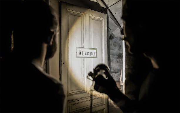 Dimly lit cellar with "Notausgang" sign during Historical Pharmacy Cellar Guided Tour.