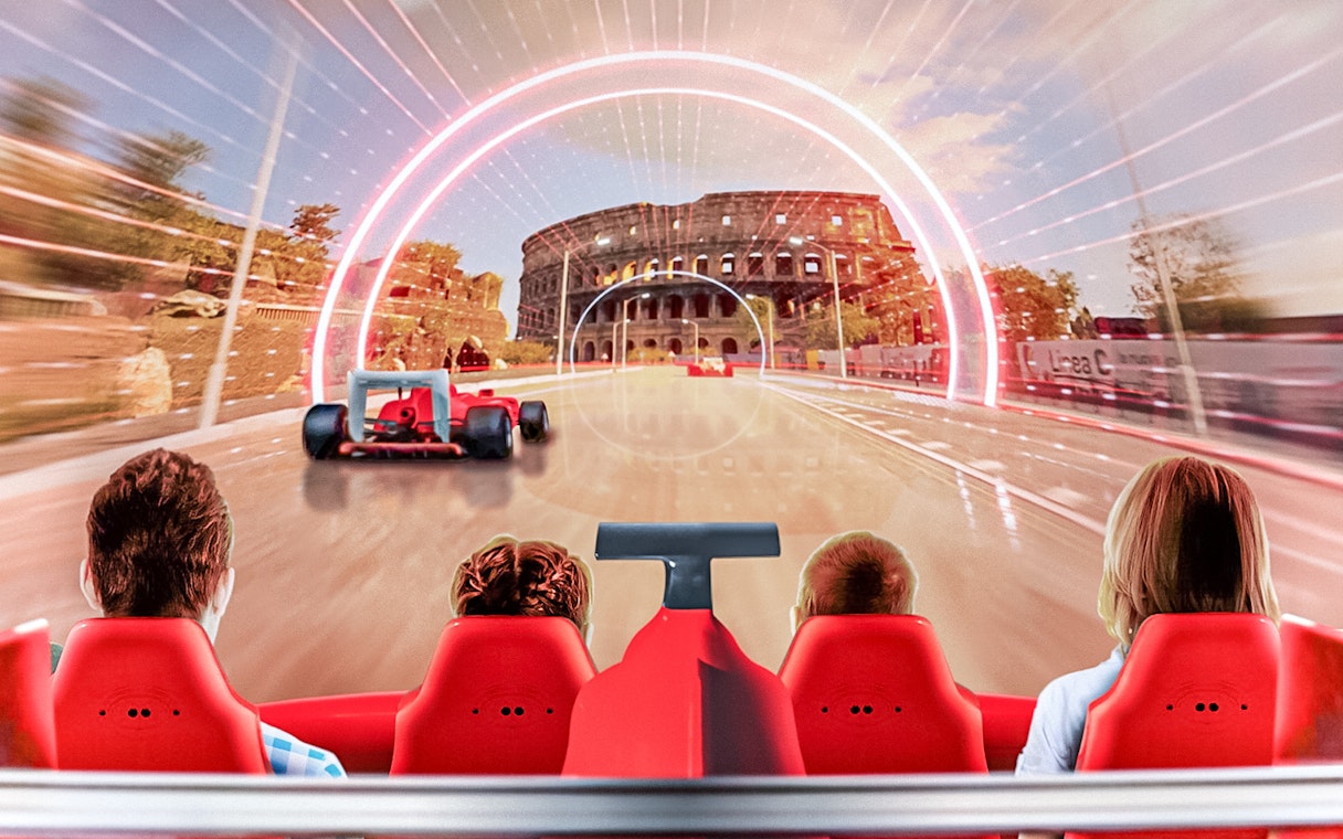 Tourists on a ride at Ferrari Land with a view of a racetrack and Colosseum backdrop.