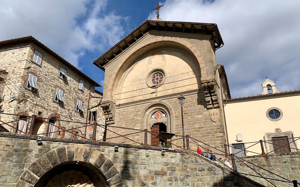 Stone church facade in Chianti Hills, Italy, under a blue sky.