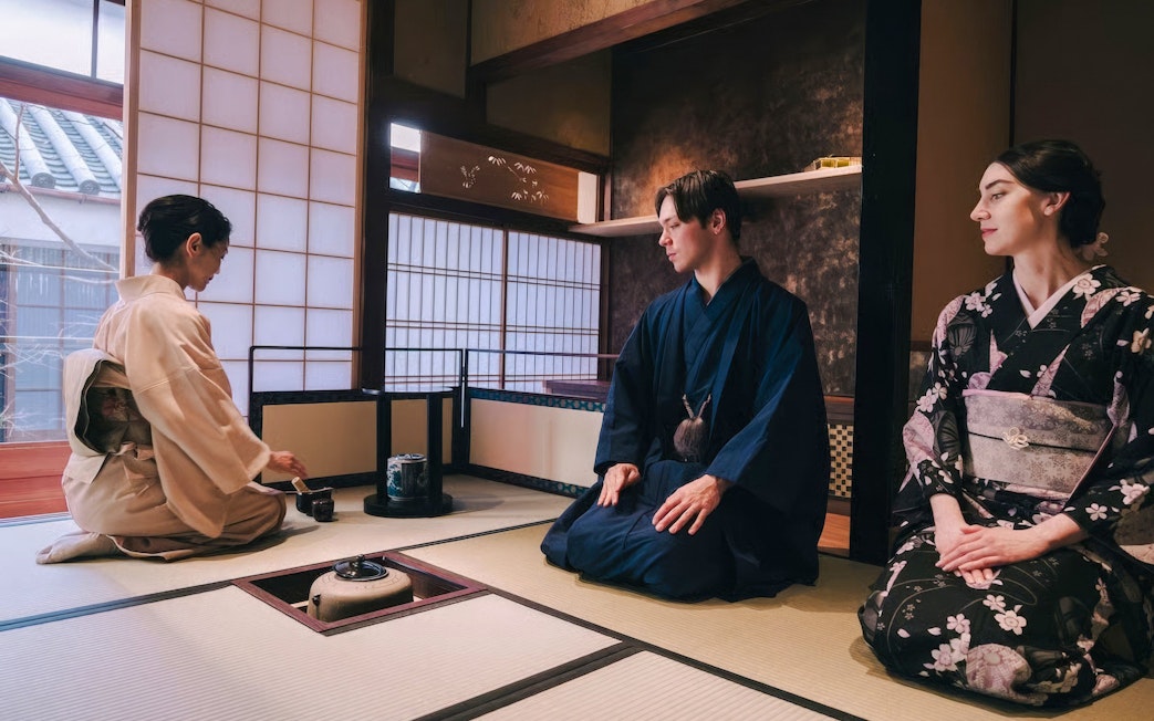 Tourists in kimono participating in a traditional Japanese tea ceremony.