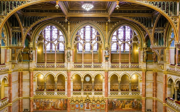 Interior of the House of Peers, Hungarian Parliament, Budapest, showcasing ornate arches and stained glass windows.