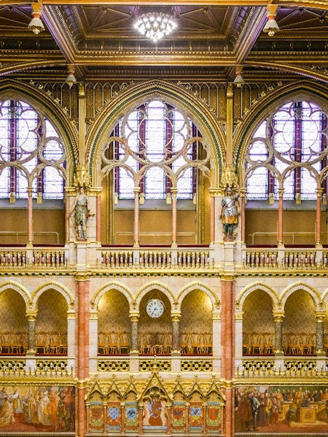 Interior of the House of Peers, Hungarian Parliament, Budapest, showcasing ornate arches and stained glass windows.