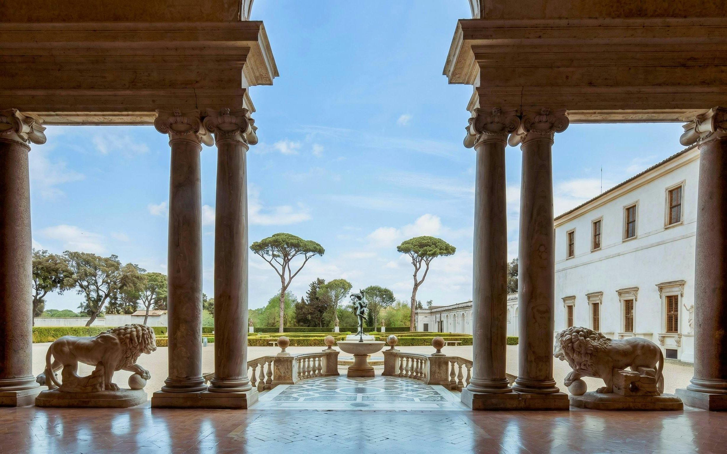 Courtyard view from Villa Medici in Rome with statues and columns.