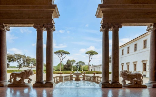 Courtyard view from Villa Medici in Rome with statues and columns.