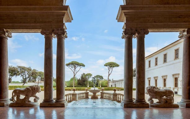 Courtyard view from Villa Medici in Rome with statues and columns.