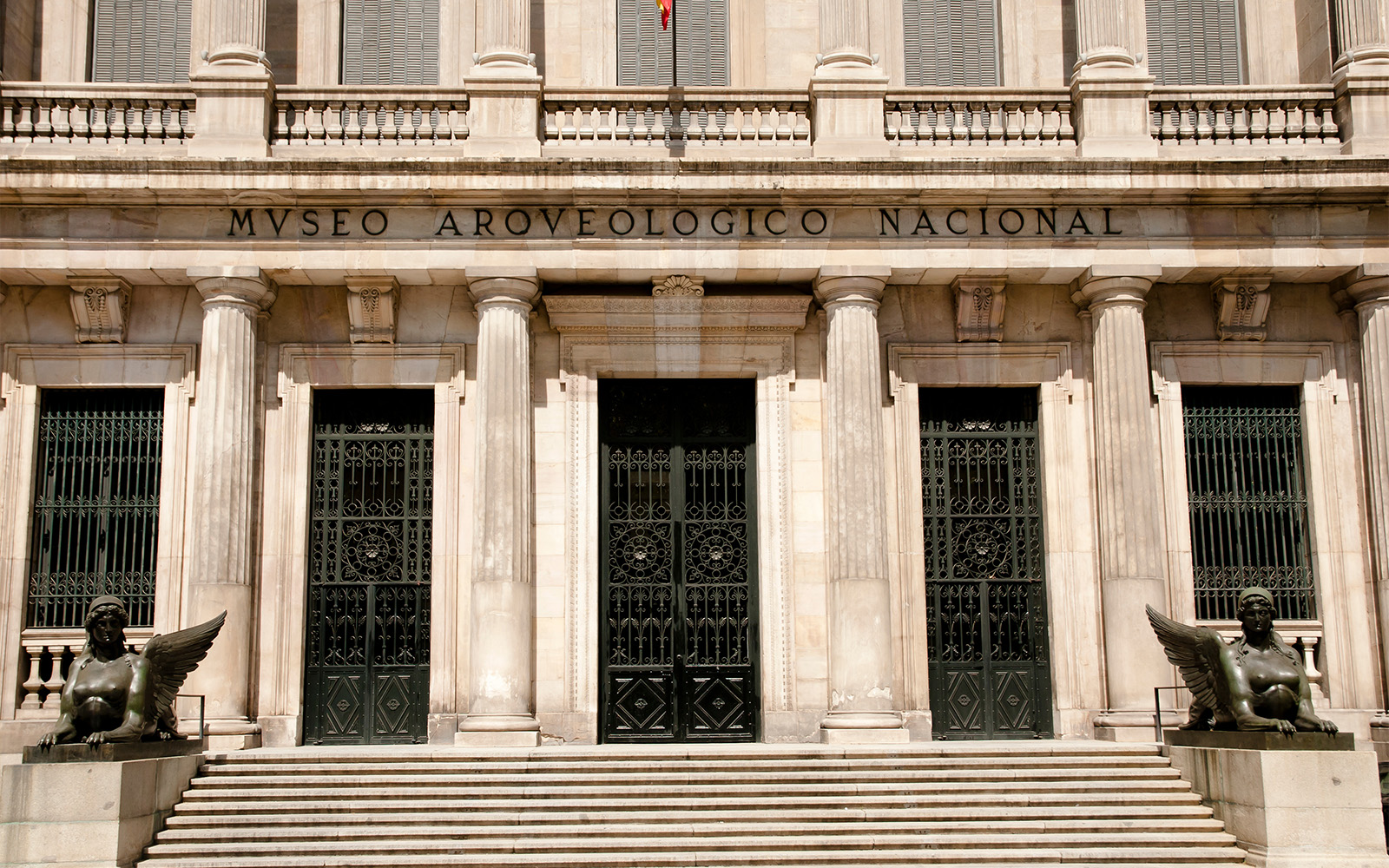 Facade of the National Archaeological Museum with columns and statues in Madrid.