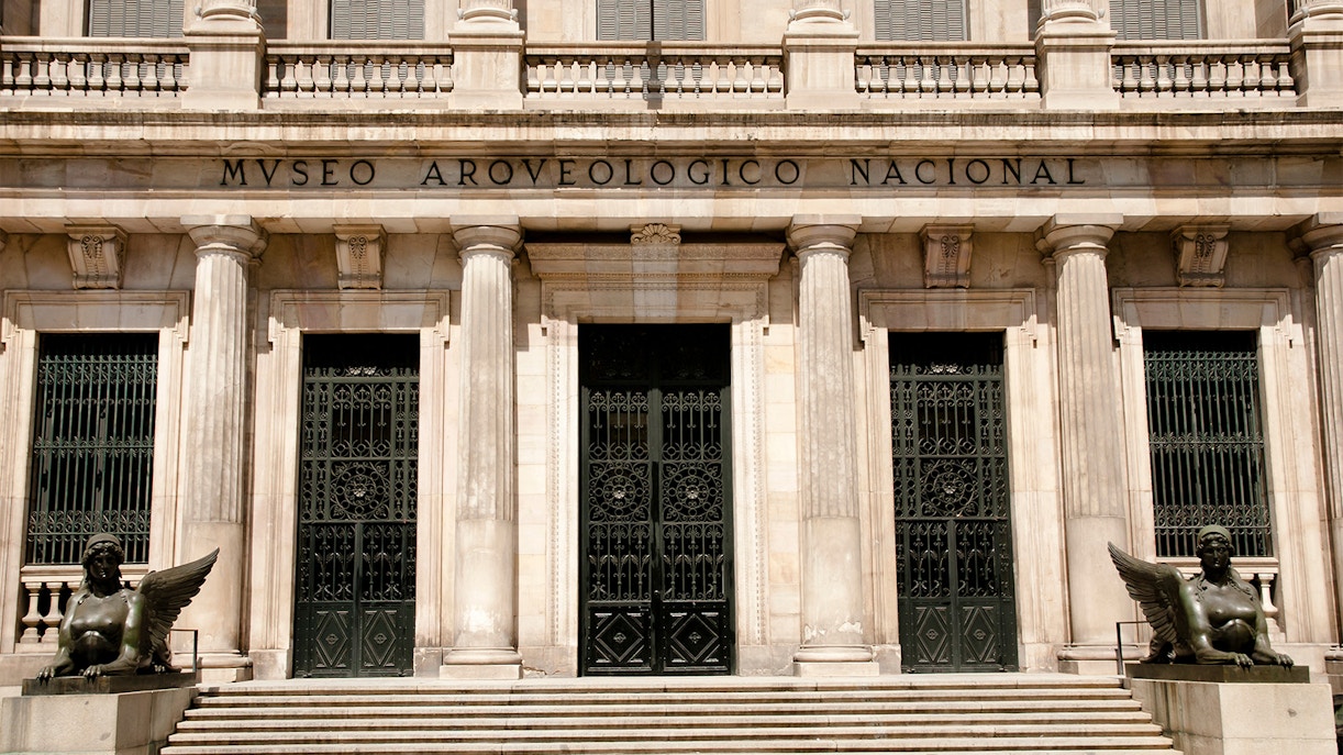 Facade of the National Archaeological Museum with columns and statues in Madrid.