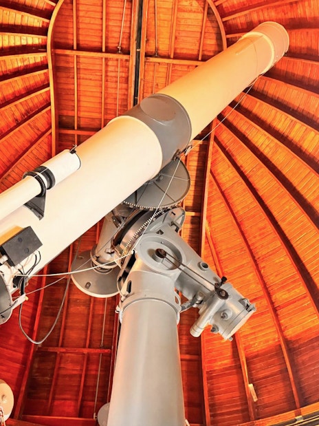 Telescope inside the Castle Gandolfo Observatory with wooden dome ceiling.
