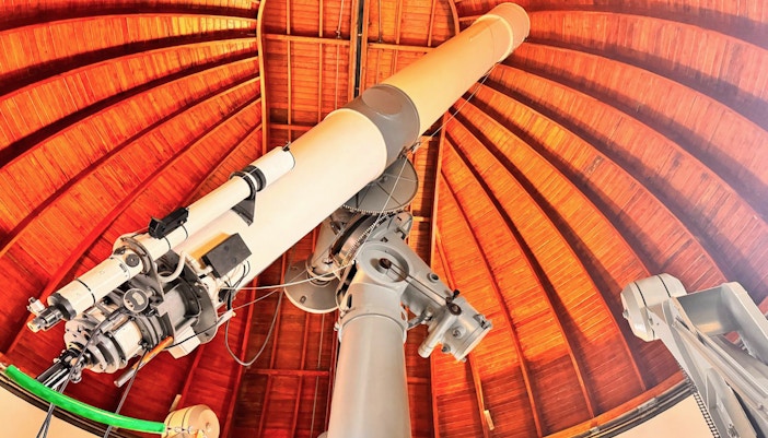 Telescope inside the Castle Gandolfo Observatory with wooden dome ceiling.