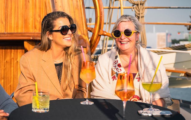 Women enjoying drinks on a boat during Amsterdam Skyline Tour.