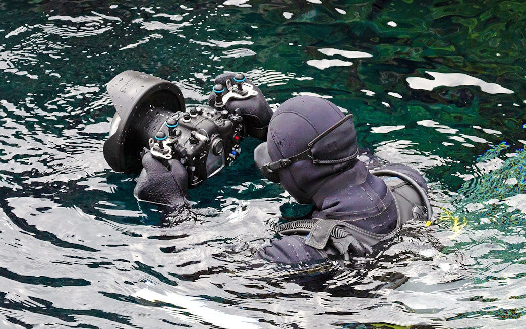 Diver photographing underwater at Silfra Fissure, Iceland.