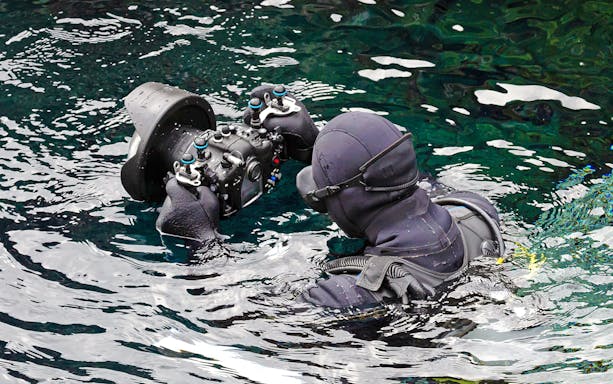 Diver photographing underwater at Silfra Fissure, Iceland.