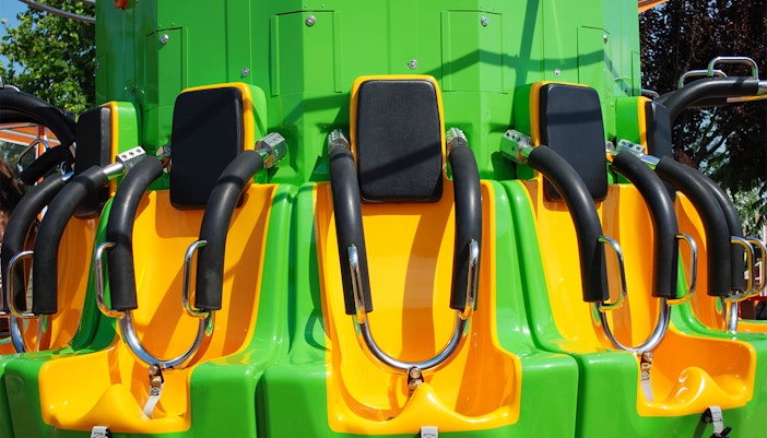 Drop tower seats with safety harnesses, bright green and yellow colors.