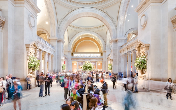 Grand entrance hall of the Metropolitan Museum of Art with visitors exploring.