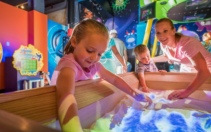 Children exploring interactive sand exhibit at Orlando science center.