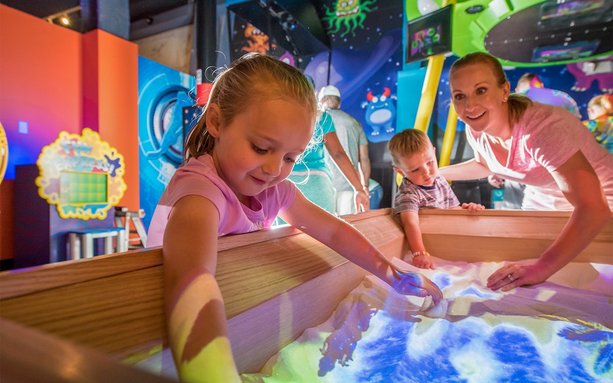 Children exploring interactive sand exhibit at Orlando science center.