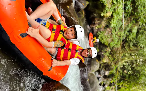 River tubing adventure in Bali with participants in helmets and life vests navigating rapids.