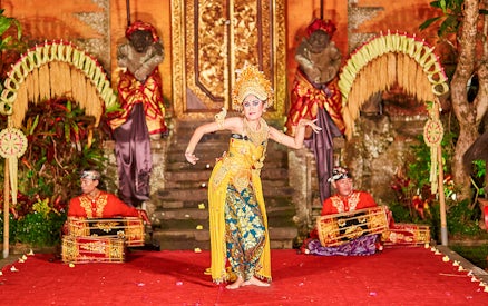 Dancer performing Legong dance at Ubud Palace, Bali with musicians in traditional attire.