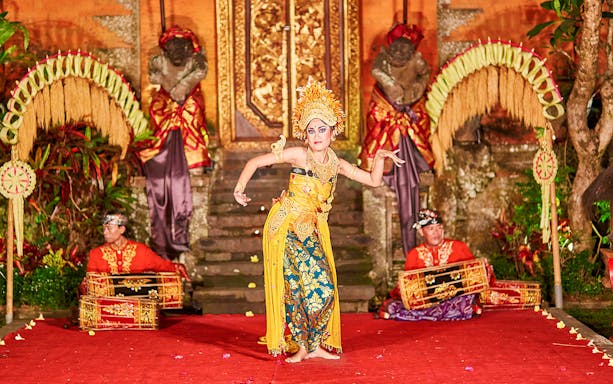 Dancer performing Legong dance at Ubud Palace, Bali with musicians in traditional attire.