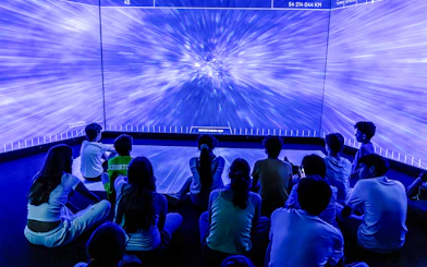 Visitors watching immersive space exhibit at Science & Industry Museum, Paris.