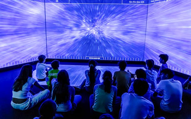 Visitors watching immersive space exhibit at Science & Industry Museum, Paris.