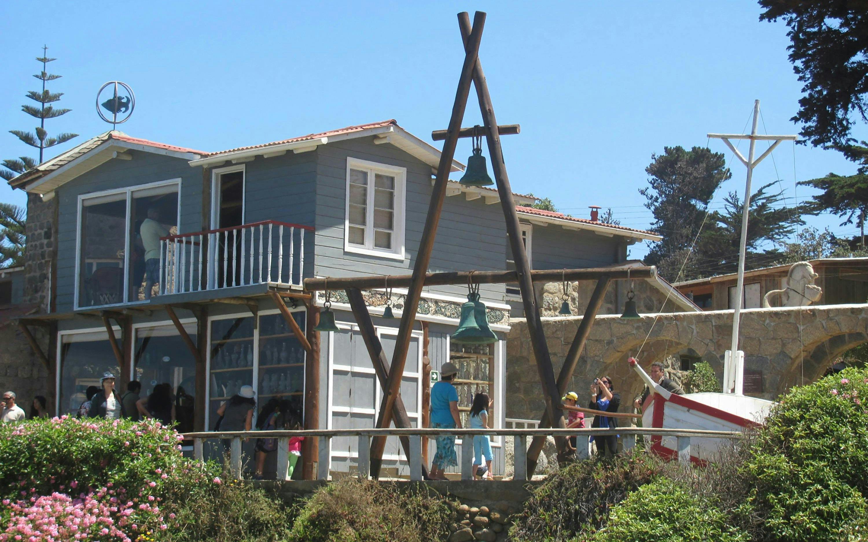 Pablo Neruda's house in Isla Negra, Chile, with visitors exploring the exterior and garden.