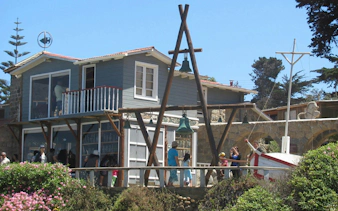 Pablo Neruda's house in Isla Negra, Chile, with visitors exploring the exterior and garden.