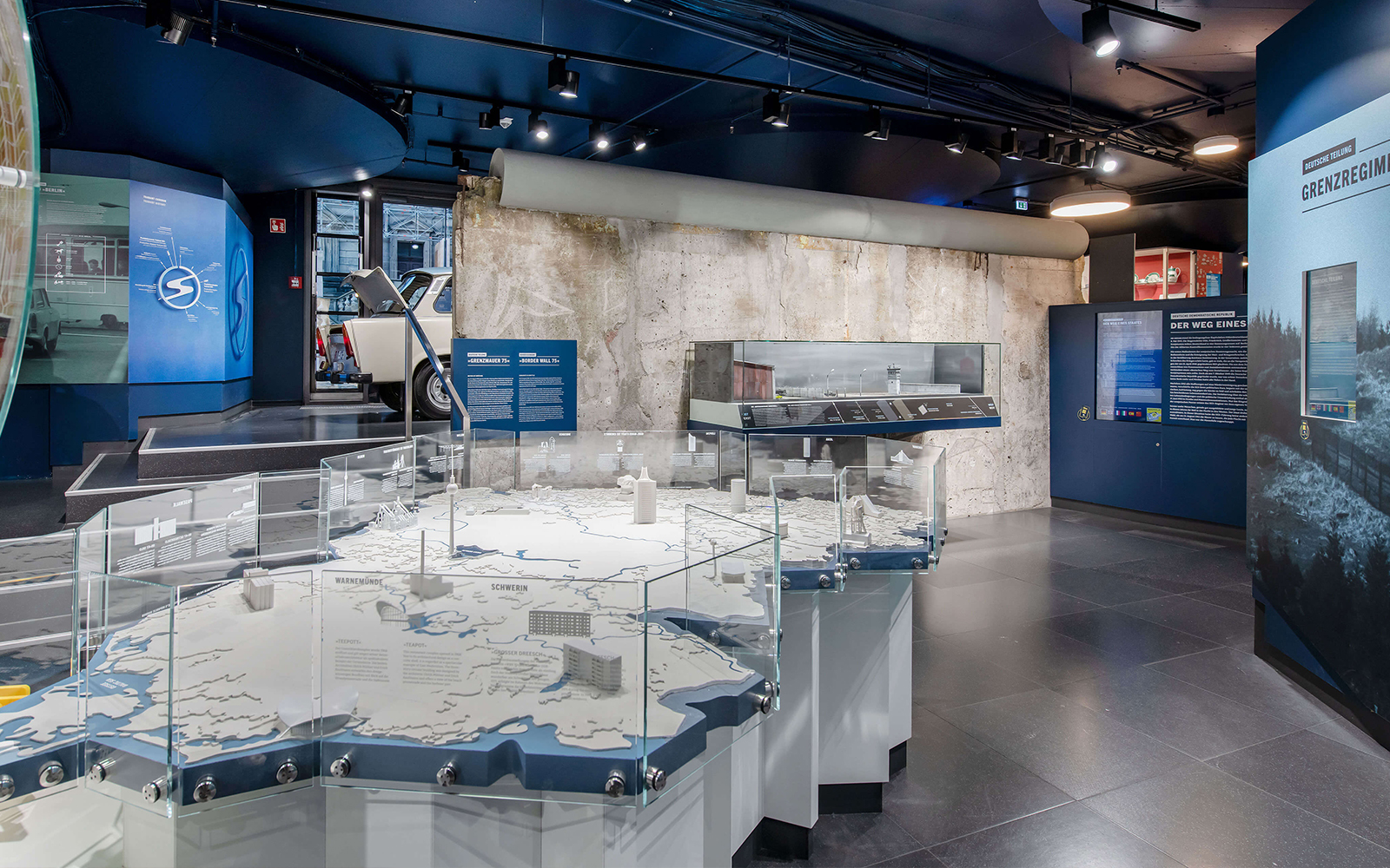 DDR Museum Berlin exhibit with Trabant car and Berlin Wall display.