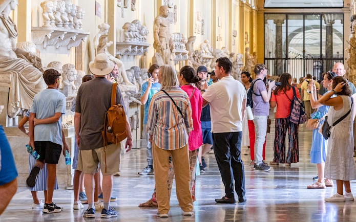Visitors exploring sculptures on a guided tour of the Vatican Museums.