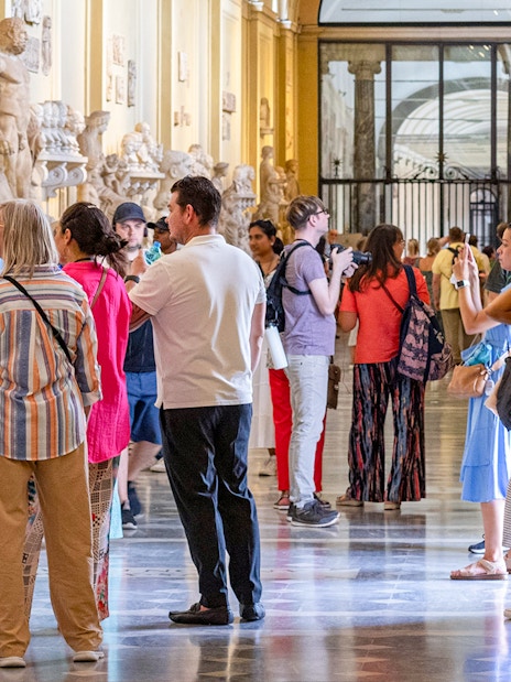 Visitors exploring sculptures on a guided tour of the Vatican Museums.