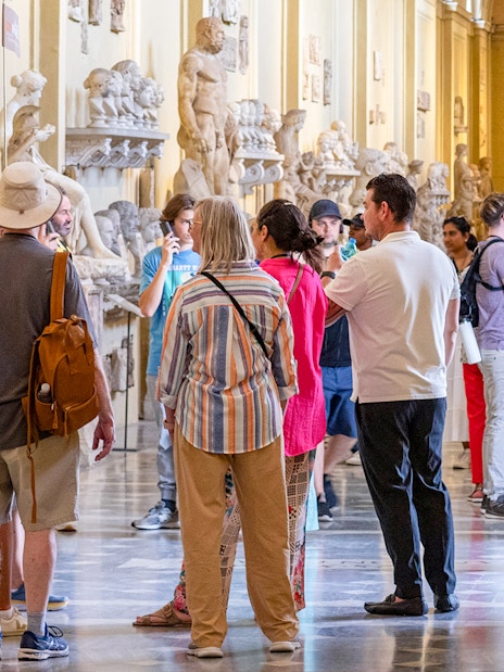 Visitors exploring sculptures on a guided tour of the Vatican Museums.