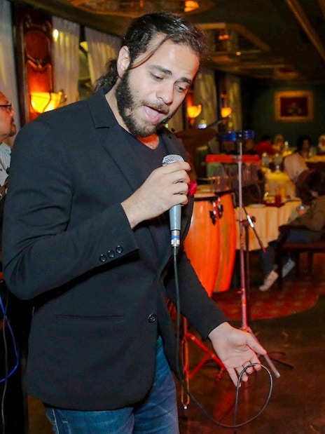 Musician performing on a luxury Nile dinner cruise with guests dining in the background.