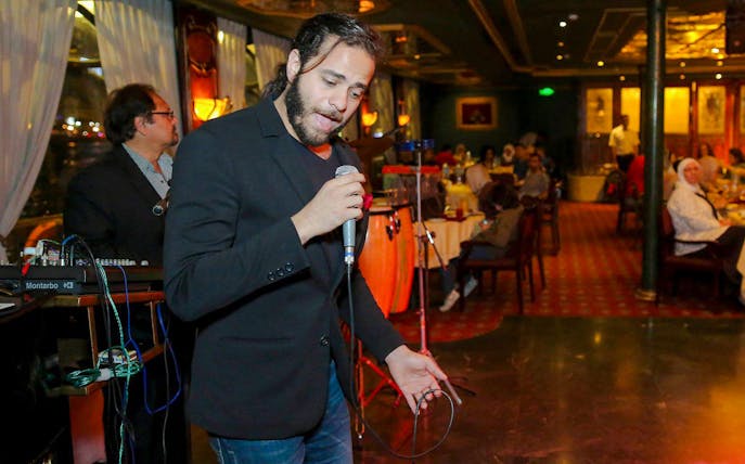 Musician performing on a luxury Nile dinner cruise with guests dining in the background.