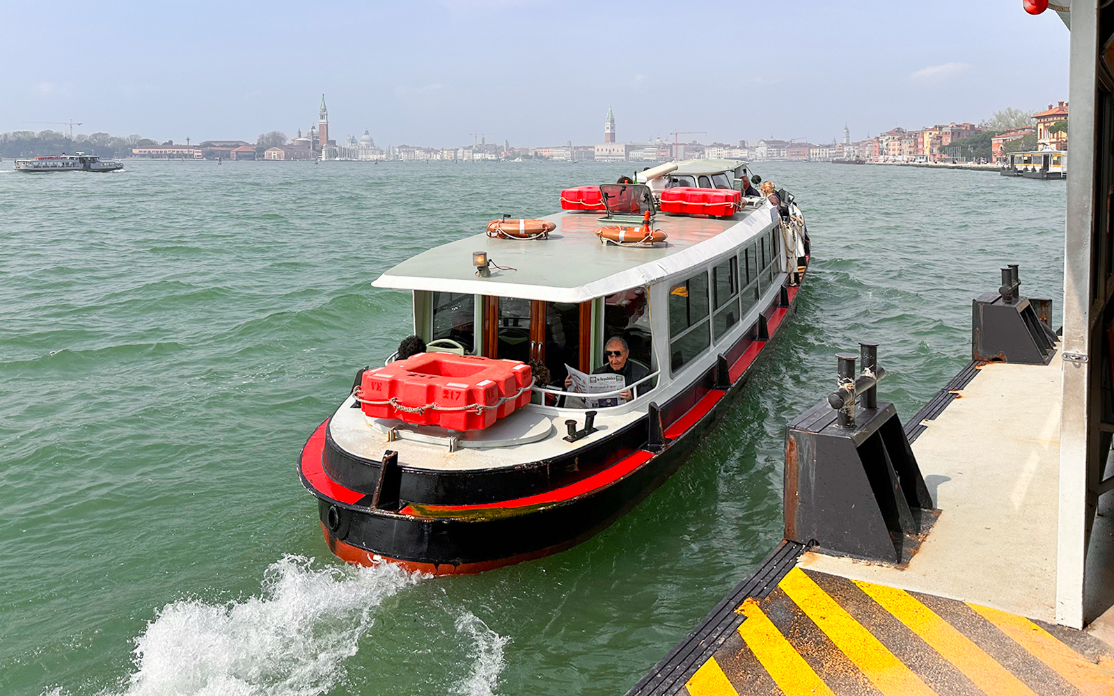 Venice Vaporetto water bus on Grand Canal with historic buildings in background.