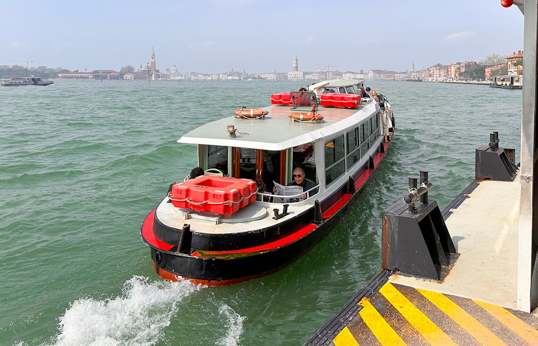 Venice Vaporetto water bus on Grand Canal with historic buildings in background.