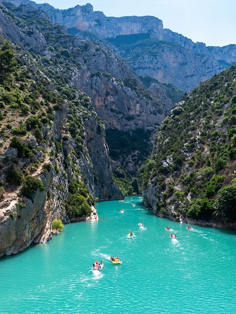 Kayakers on turquoise waters of Gorges du Verdon, surrounded by steep cliffs and lush greenery.