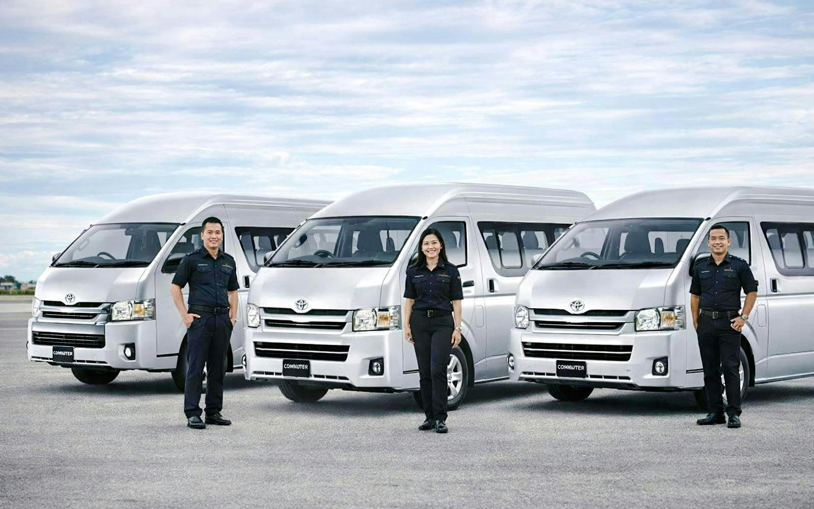 Crew standing in front of vans for private airport transfer in Bangkok.