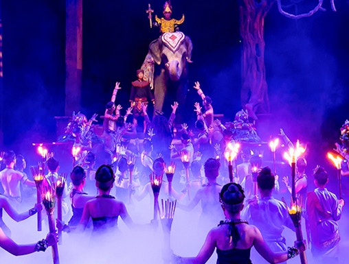 Performers with torches surround an elephant and rider on stage at Phuket Fantasea show.