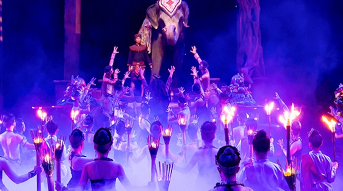 Performers with torches surround an elephant and rider on stage at Phuket Fantasea show.