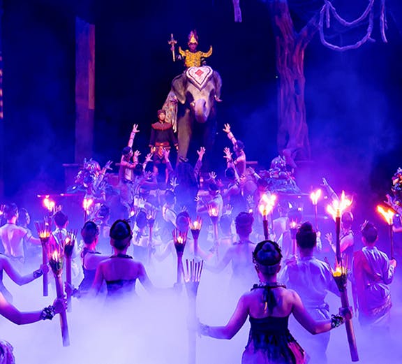 Performers with torches surround an elephant and rider on stage at Phuket Fantasea show.