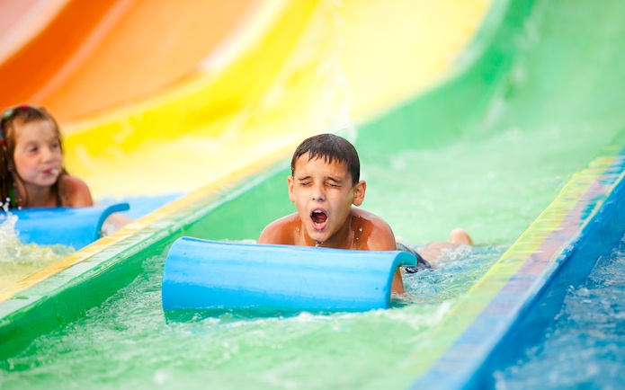 Child sliding down colorful water slide at a waterpark.