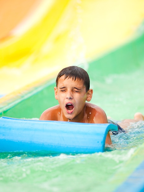 Child sliding down colorful water slide at a waterpark.