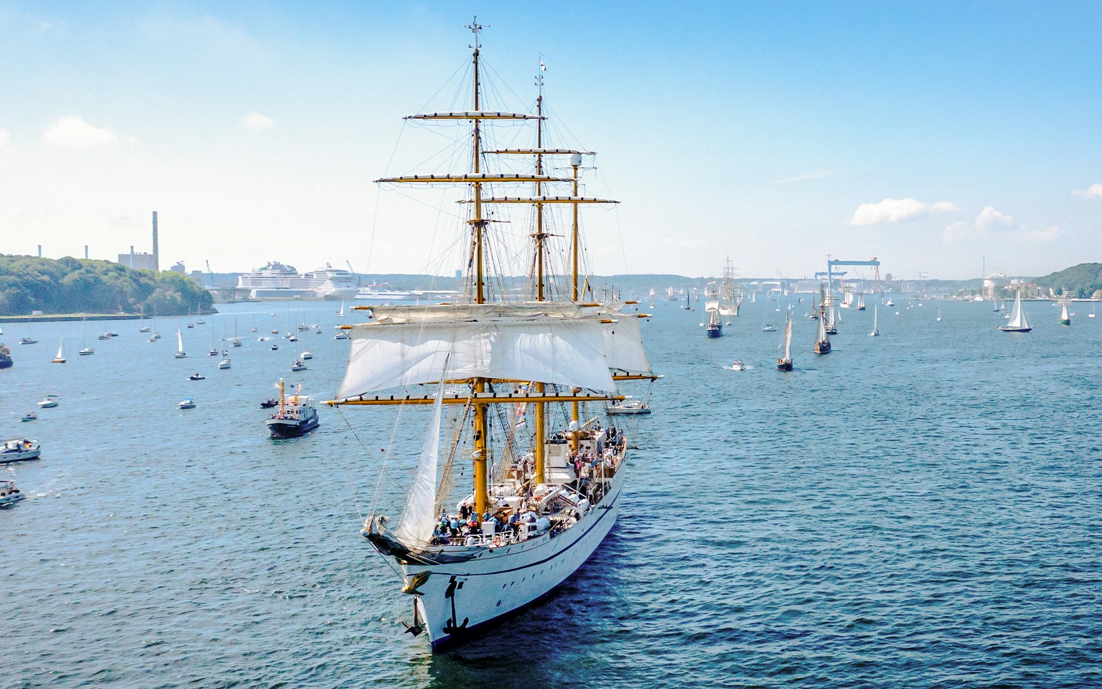 Europa ship sailing near a coastal city with historic architecture in the background.