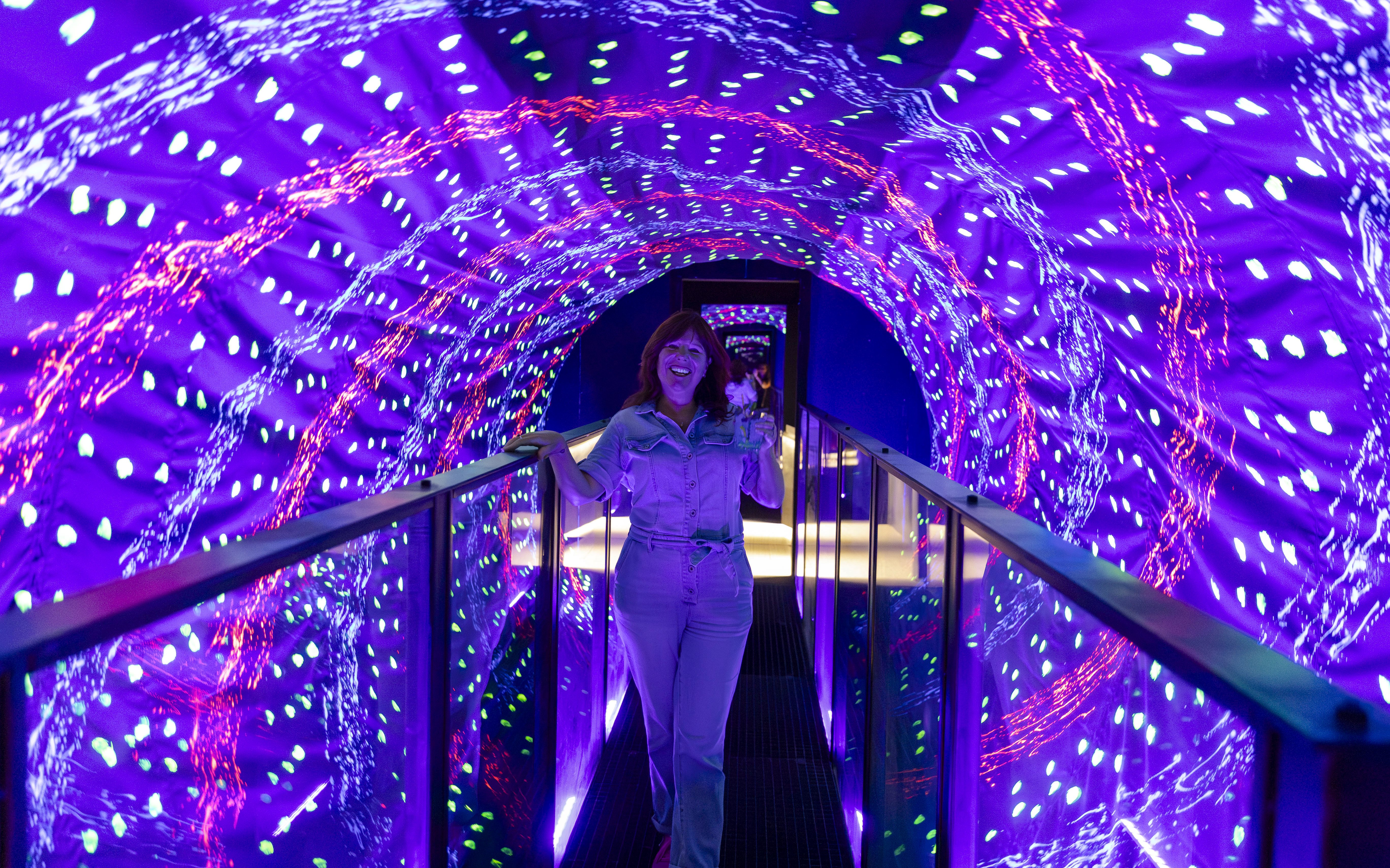 Guest walking through a vibrant light tunnel at the Museum of Illusions Amsterdam.