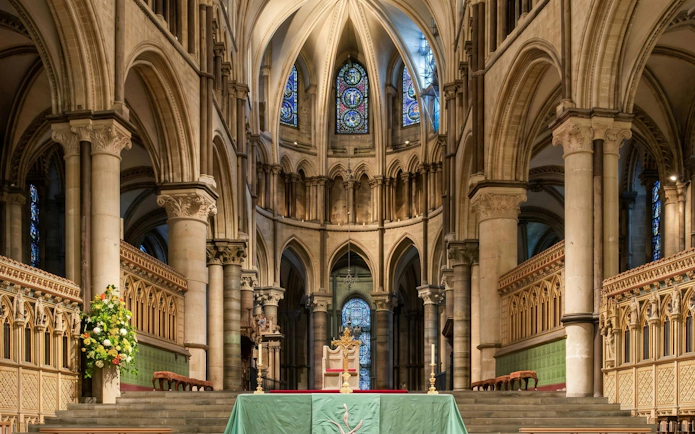 Interior view of Canterbury Cathedral's nave with ornate arches and stained glass windows.