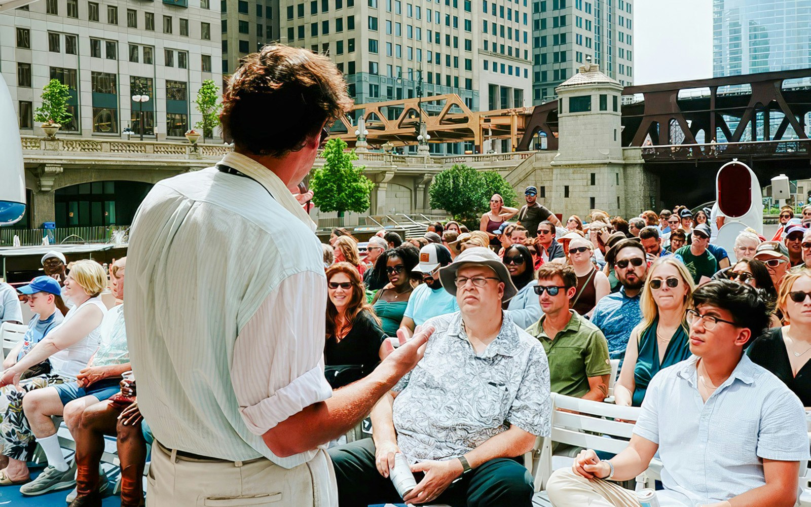 Tour guide speaking to a group on a Chicago River Architecture Tour with city buildings in the background.
