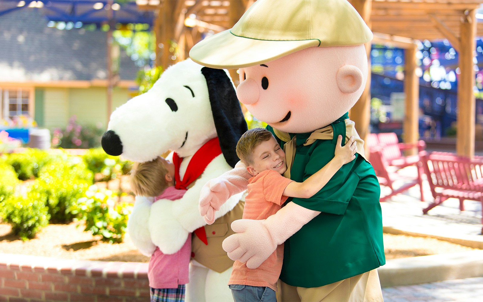Children hugging Snoopy and a character at Six Flags Carowinds, CAMP SNOOPY®.