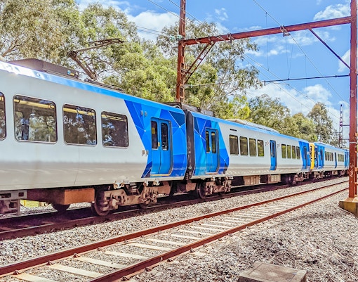 Train traveling through lush greenery near Melbourne Skydeck.