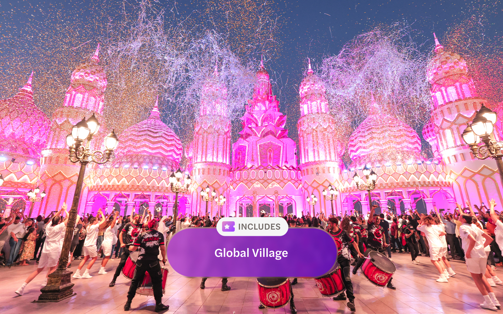 Drummers performing at Global Village Dubai with pink-lit architecture and festive crowd.