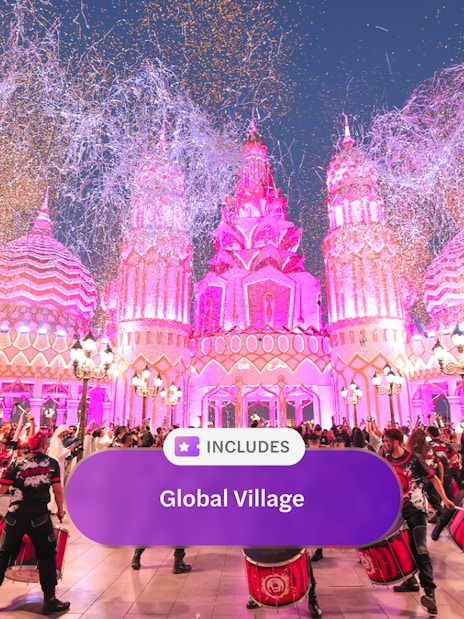 Drummers performing at Global Village Dubai with pink-lit architecture and festive crowd.
